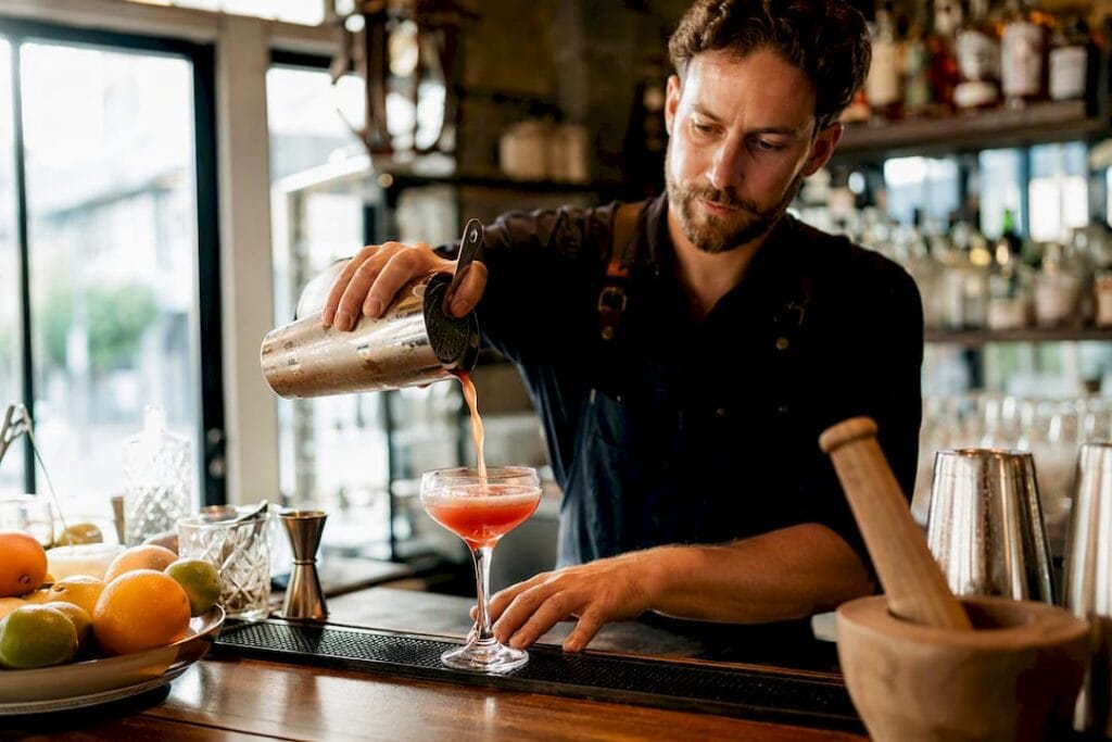 Un mixologue prépare un cocktail devant les invités lors d’une soirée événementielle.