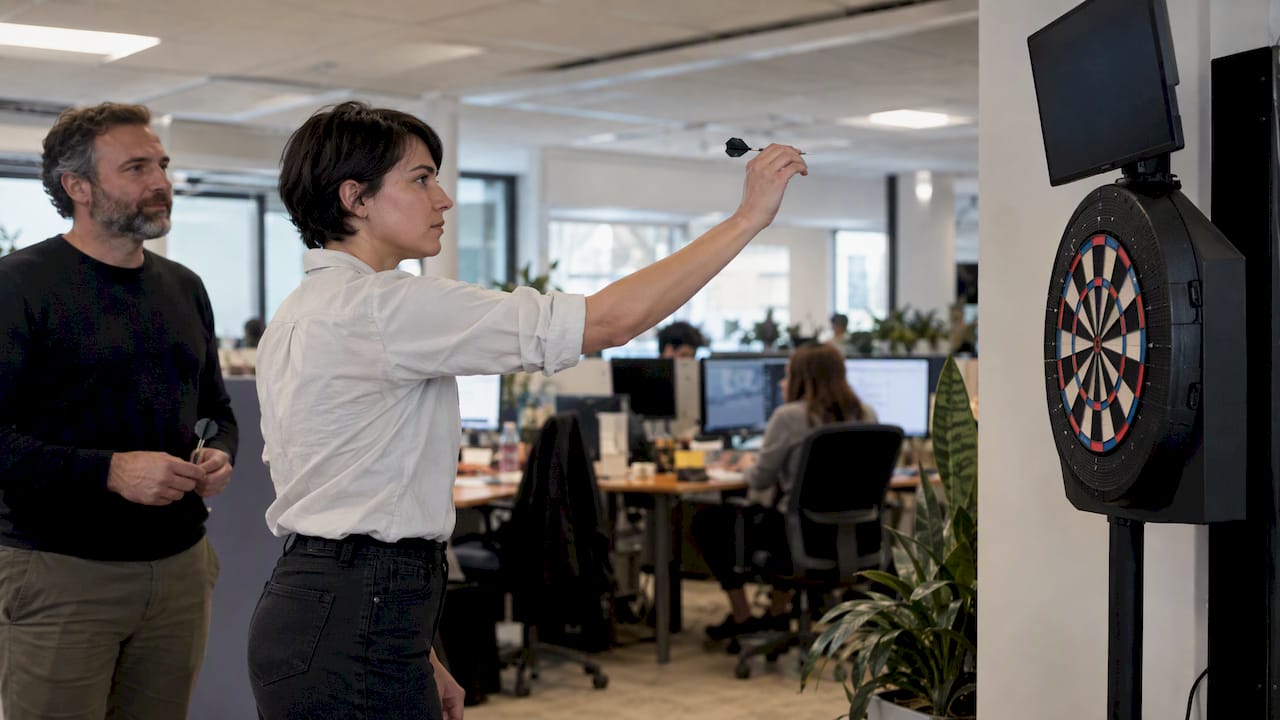 Un collègue lance une fléchette sur une cible connectée